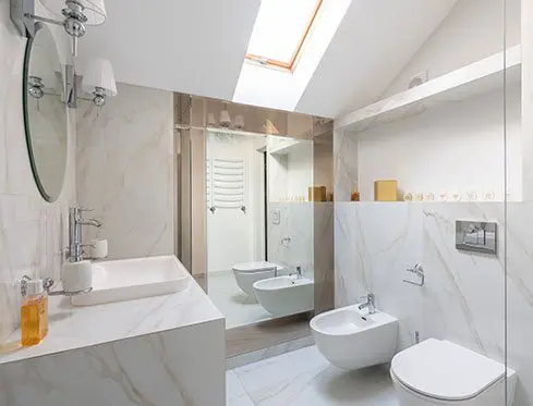 A bathroom with white fixtures and a skylight.